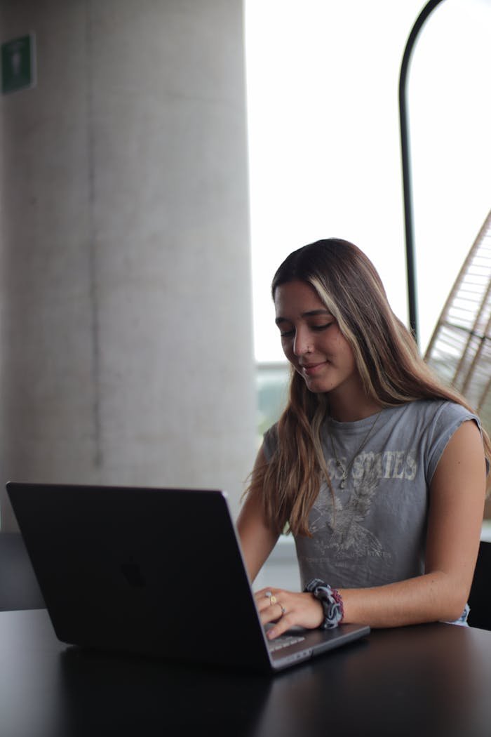 Young woman using laptop, concentrating on online studies indoors.